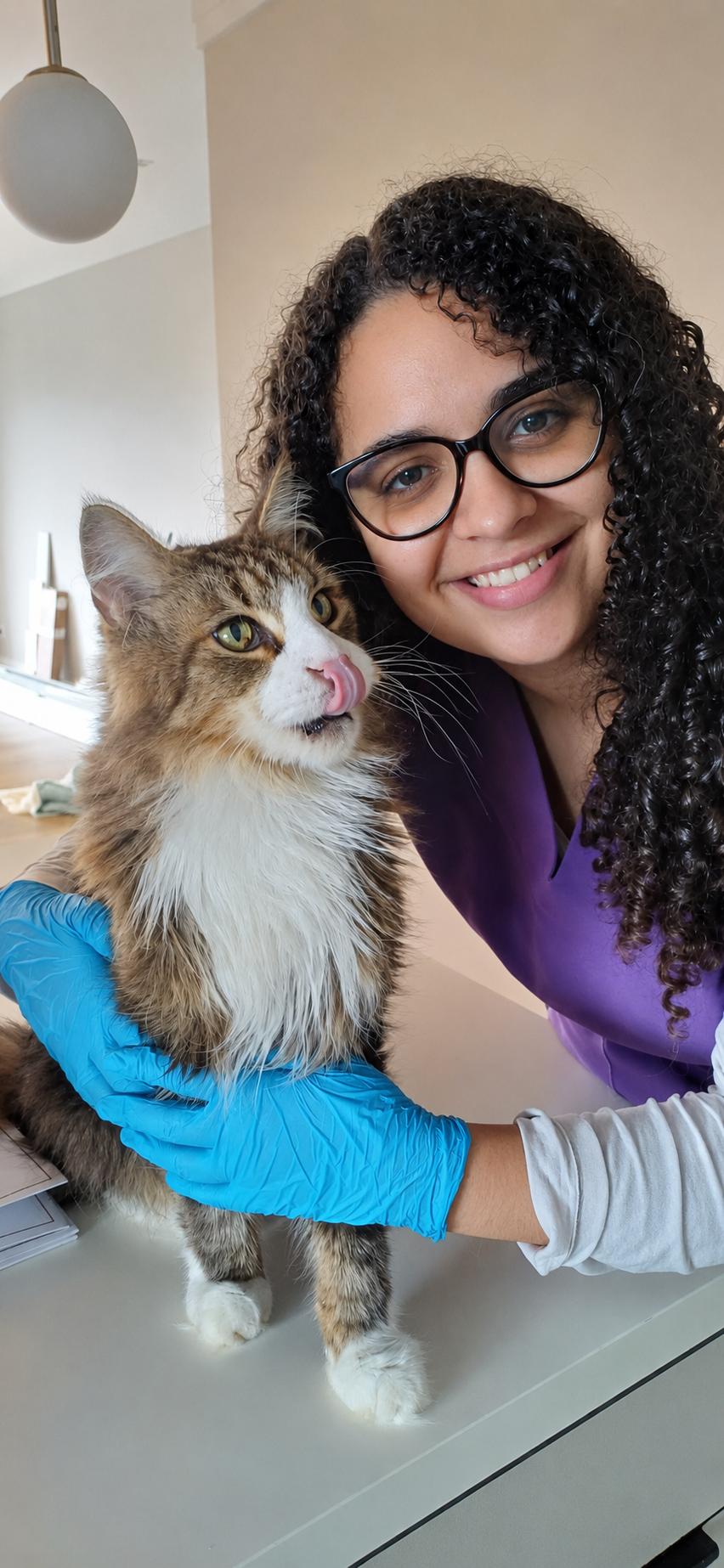 Dra. Nathália Ribeiro sorrindo ao lado de um gato durante atendimento domiciliar